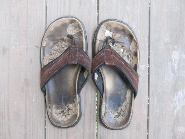 Photograph of a pair of sandals that have definitely seen better days.