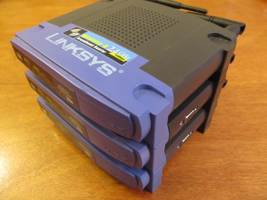 Photograph of 3 Linksys WRT 54G units, stacked.