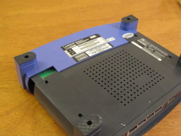 Photograph of a WRT 54G unit, upside down with its case partially slid off.