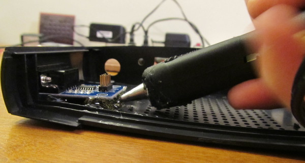 Photograph of the application of hot glue as a mounting substrate to secure the serial module.